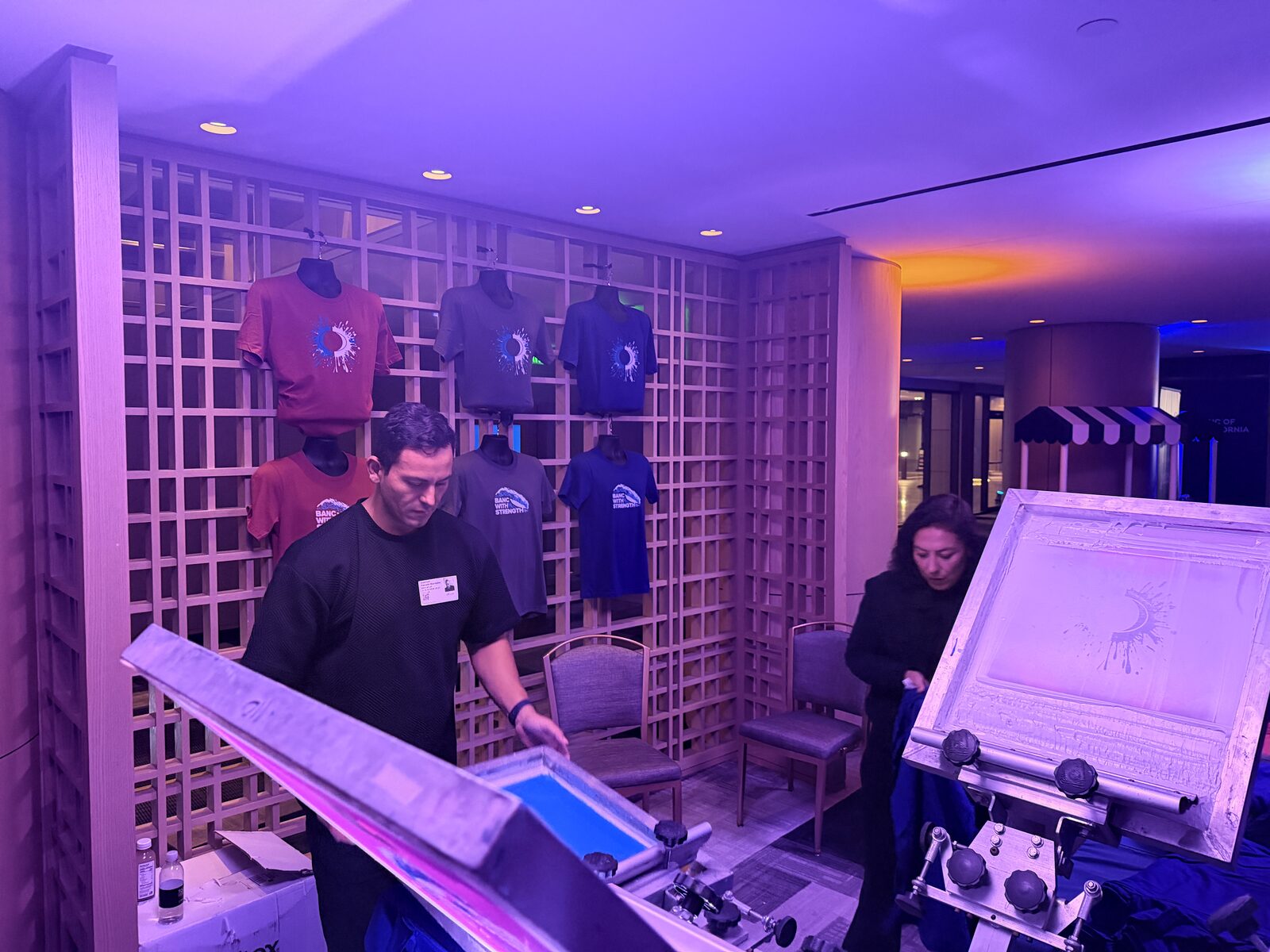 Wall of freshly printed tour shirts hung behind a concert merch station
